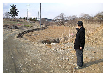 ▲ 경산 진량읍 평사리 왕국회관∼평사2길을 연결하는 마을안길 확장 포장 공사 구간에 편입되는 한 지주가 도로 개설 구간을 가리키고 있다.