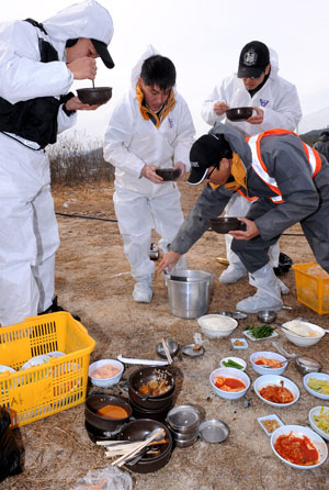 구제역 사태가 장기화 조짐을 보이면서 주거지와 멀리 떨어진 이동통제초소 방역근무자들이 추위와 스트레스에 시달리고 있다. 휴일인 12일 오후 봉화군 공무원들이 배달된 국밥을 서서 먹으며 때늦은 점심을 해결하고 있다. 정운철기자 woon@msnet.co.kr