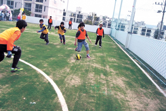 시민성결교회 앞마당에 설치된 풋살장과 그곳에서 축구 경기를 하는 어린이들.