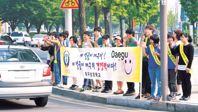 ▲9일 오전 대구남양학교 학생과 교사들이 수성구 두산오거리에서 출근길 운전자들에게 미소친절 캠페인을 벌이고 있다.