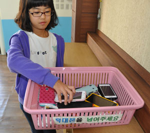 대구 달서구 파호초교의 한 학생이 교실에 마련된 바구니에 휴대전화를 보관하고 있다.