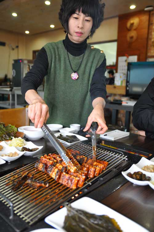 강나루집 주인 유금옥 씨가 양념소스를 바른 초벌구이를 가져와 손님 상에서 재벌구이로 풍천장어 양념구이의 진수를 선보이고 있다.