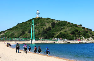 축산항 죽도산을 배경 삼아 걷고 있는 관광객들.