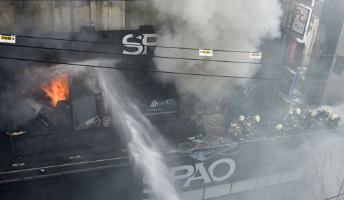 27일 오후 대구 동성로 3가 상가 건물에서 발생한 불을 끄려고 3층 난간에 올라간 소방관들이 불길이 거세지자 옆으로 물러나고 있다. 우태욱기자 woo@msnet.co.kr