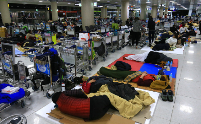 사상 초유의 제주공항 항공기 중단 사태가 3일째 이어진 25일 새벽 고단 하루를 마친 체류객들이 제주공항 여객터미널에서 잠을 자고 있다. 연합뉴스