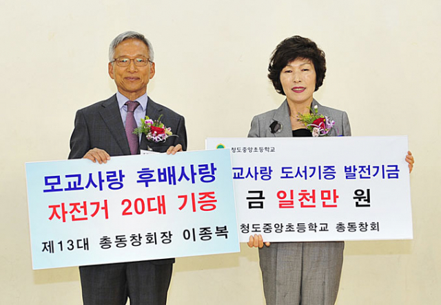 24일 열린 청도 중앙초등학교 총동창회 정기총회에서 이종복(왼쪽) 회장이 민은희 교장에게 모교사랑 도서기증 발전기금 1천만원과 자전거 20대를 전달하고 있다. 중앙초교 총동창회 제공