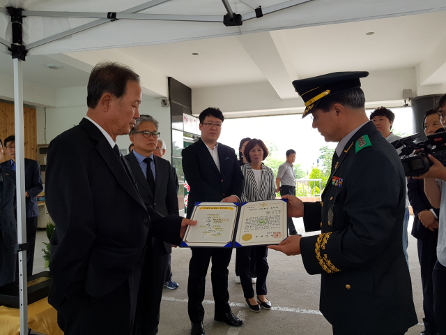 19일 열린 호국영웅 귀환행사에서 이학기 국방부 유해발굴감식단장이 고 윤경혁 일병의 아들 윤팔현 씨에게 전사자 신원확인 통지서를 전달하고 있다. 국방부 유해발굴감식단 제공.