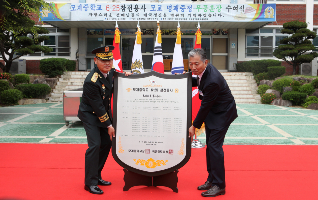 19일 경북 청도 모계중학교에서 열린 6·25참전용사 모교 명패증정 행사에서 김문곤(소장·좌측) 인사사령관이 학교장에게 명패를 전달하고 있다. 육군 제공