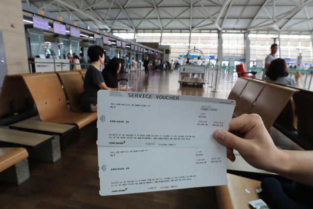 아시아나 항공이 사흘째 계속되고 있는 기내식 공급 차질과 이로 인한 운항 지연사태에 대해 공식 사과한 3일 인천국제공항에서 한 승객이 항공기 지연으로 인해 지급받은 1만원권 서비스 바우쳐를 보여주고 있다.