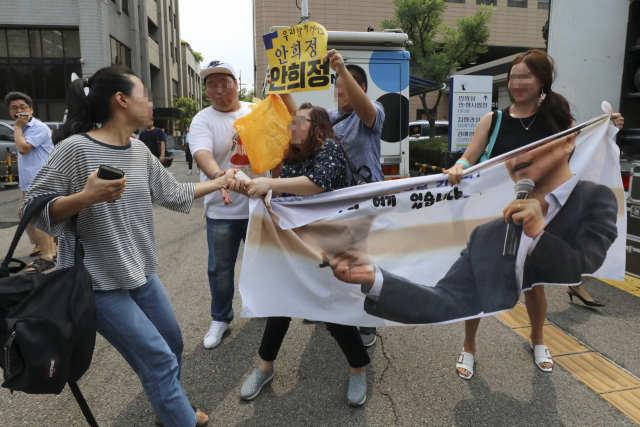 비서에 대한 성폭력 혐의로 기소된 안희정 전 충남지사가 1심에서 무죄를 선고받은 14일 오전 서울서부지법 앞에서 한 여성이 안 전 지사를 지지하는 사람의 현수막을 뺏으려 하고 있다. 연합뉴스