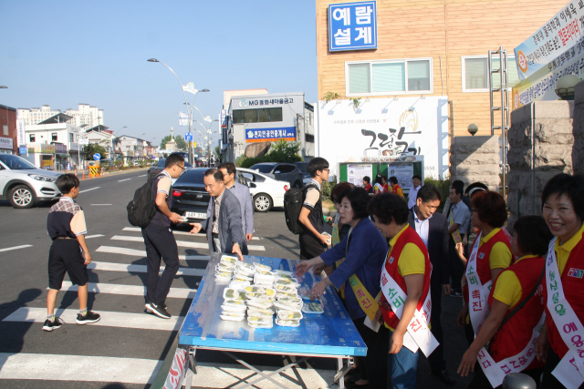 한국여성농업인 청도군연합회가 20일 청도 모계중고에서 쌀 소비촉진 행사를 갖고, 등교하는 학생들에게 떡을 나눠주고 있다. 모계중고 제공