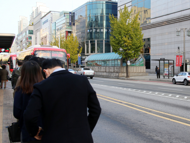 카카오 카풀 영업을 반대하며 택시 파업이 시작된 18일 오전 출근자들이 일산 주엽역 인근 버스 정류소에서 버스를 기다리고 있다. 맞은편 택시 승차장에는 한 승객이 택시를 기다리고 있다. 연합뉴스