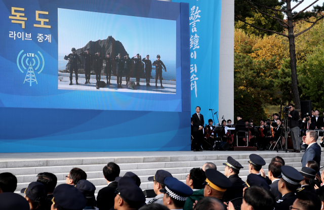 문재인 대통령이 25일 오후 서울 용산구 백범기념관에서 열린 제73주년 경찰의 날 기념식에서 독도를 경비하고 있는 독도경비대원들과 화상 통화하다 경례를 하고 있다. 25일은 경찰의 날이자 독도의 날이다. 연합뉴스