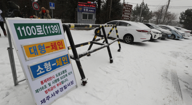 제주 산지에 대설주의보가 내려진 28일 오전 어승생 삼거리 입구에서 체인이 없는 소형차량과 대형차량의 1100로 진입을 통제하고 있다. 연합뉴스 #제주공항