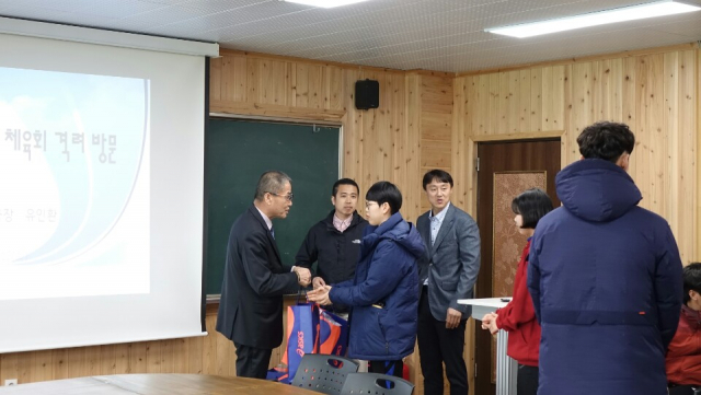 거창군체육회 유인환사무국장이 체육복 등을 전달하며 학생들을 격려하고 있다.