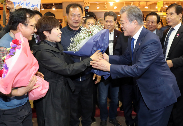 문재인 대통령이 22일 대구 북구 칠성시장에서 상인들의 꽃다발을 받고 있다. 연합뉴스