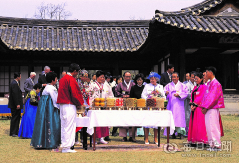 엘리자베스 2세 영국 여왕이 안동 주민들이 하회마을 담연재 마당에 차린 자신의 73회 생일상을 보면서 웃음을 짓고 있다. 안동시 제공