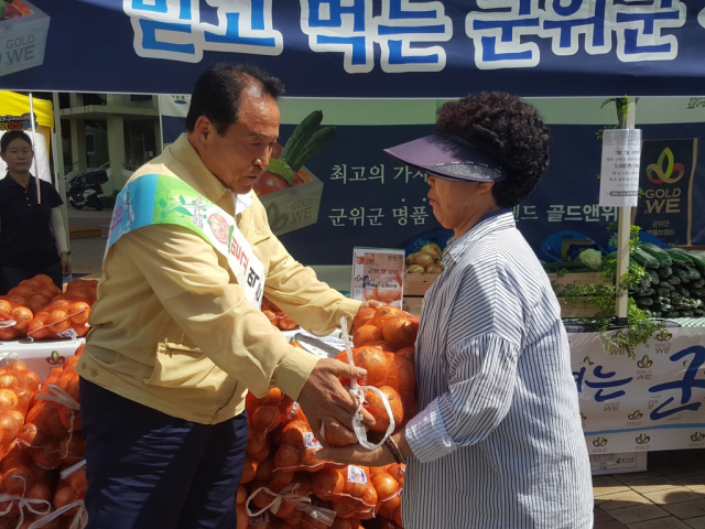 김영만 군위군수가 2일 대구시 북구 화성그랜드파크 앞에서 소비자에게 직접 양파를 판매하고 있다. 군위군 제공