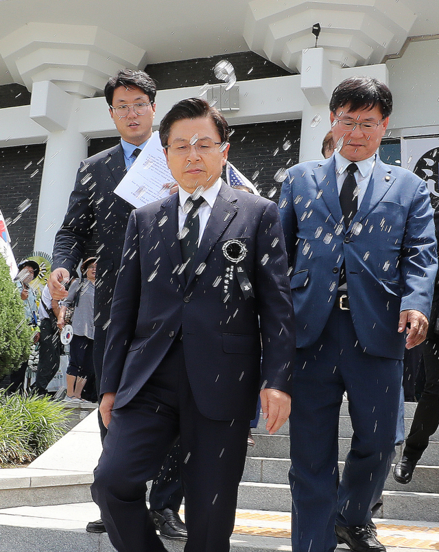 황교안 자유한국당 대표가 19일 서울 동작구 국립서울현충원 현충관에서 열린 이승만 대통령 서거 54주기 추모식이 끝난 뒤 박근혜 전 대통령 지지자들로부터 항의와 함께 물 세례를 받고 있다. 연합뉴스