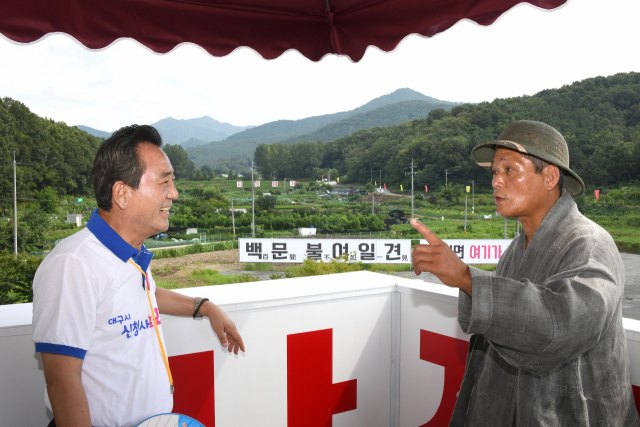 김문오 달성군수(왼쪽)와 김경우 풍수지리 전문가가 딜성군 화원읍 대구시 신청사 유치 후보지(LH분양홍보관)에서 서로 의견을 나누고 있다. 멀리 보이는 산봉우리가 주산인 함박산이다. 달성군 제공