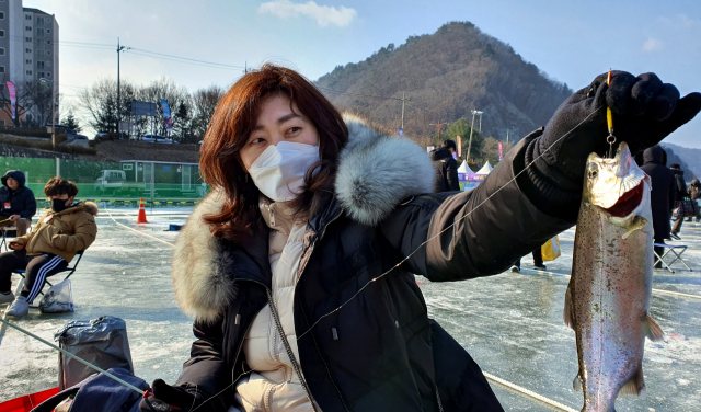 화천 산천어 축제장을 찾은 한 시민이 낚시로 잡아올린 물고기를 들어보이고 있다.