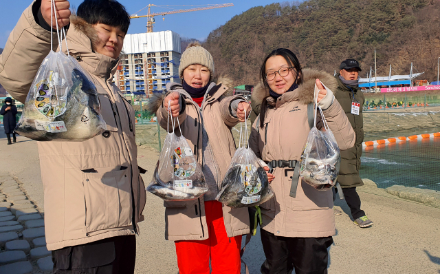 산천어 축제장을 찾은 많은 시민들이 잡은 물고기를 들어보이고 있다.