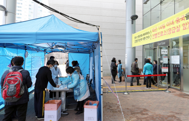 22일 부산 해운대백병원 입구에서 방문객들이 신종 코로나바이러스 감염증(코로나19) 확산 저지를 위해 발열 체크 등 문진을 받고 병원 안으로 들어가고 있다. 연합뉴스