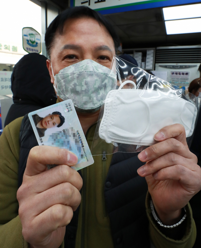 공적 마스크 5부제가 시행되는 9일 오전 서울 종로5가 인근 한 약국에서 마스크를 구매한 한 시민이 신분증과 마스크를 보여주고 있다. 마스크 5부제에 따라 출생연도 끝자리가 1과 6이면 월요일, 2와 7이면 화요일, 3과 8이면 수요일, 4와 9이면 목요일, 5와 0이면 금요일에 마스크를 살 수 있다. 연합뉴스