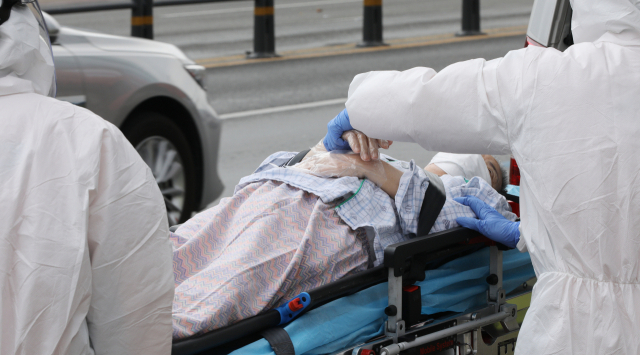 지난 19일 오후 대구 서구 한사랑요양병원에서 구급대원이 코로나19 확진자를 병원으로 이송하고 있다. 김영진 기자 kyjmaeil@imaeil.com