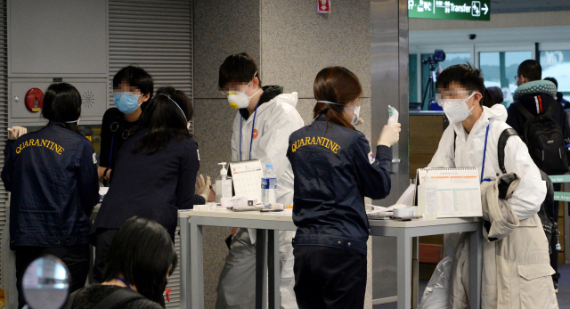 검역당국이 유럽발 전여행객들에 대해 코로나19전수검사를 시행하고 있는 가운데 23일 오전 인천국제공항 1터미널 도착층의 선별진료소에서 런던발 항공기를 이용해 입국한 유증상자들이 검역관과 이야기를 하고 있다. 연합뉴스