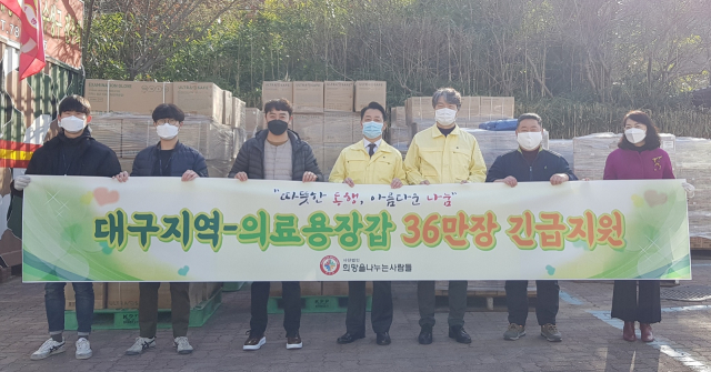 (사)희망을나누는사람들이 수성구청에 전달한 의료용 장갑 앞에서 기념촬영을 하고 있다. 수성구 제공