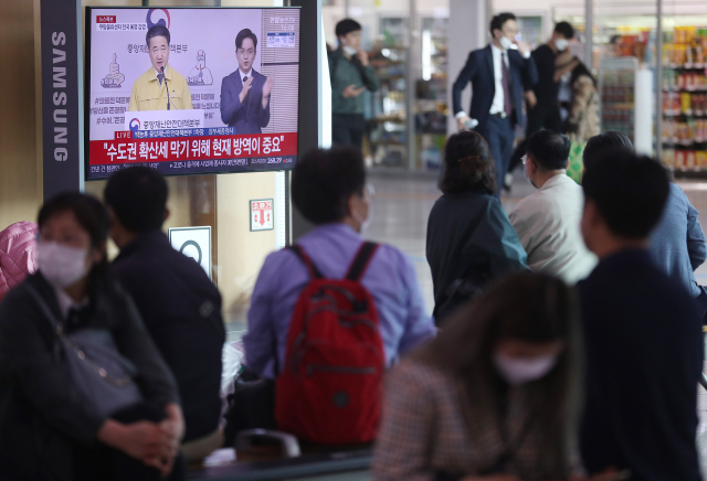 28일 서울역에서 시민들이 박능후 중앙재난안전대책본부 1차장의 코로나19 긴급관계장관회의 결과 브리핑 생중계를 시청하고 있다. 연합뉴스