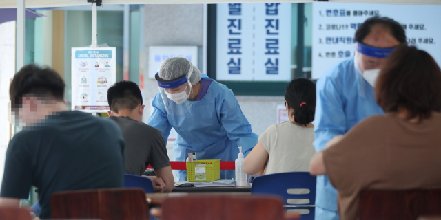 12일 오후 서울 강남구보건소에 설치된 선별진료소에서 시민들이 신종 코로나바이러스 감염증(코로나19) 검사를 받기에 앞서 문진표를 작성하고 있다. 연합뉴스