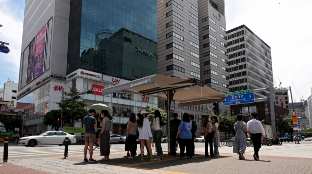 대구지역 낮 최고기온이 31.3도를 기록한 16일 오후 시민들이 중구 동성로 횡단보도 앞에 설치된 스마트 그늘막에서 따가운 햇볕을 피하고 있다. 김영진 기자 kyjmaeil@imaeil.com