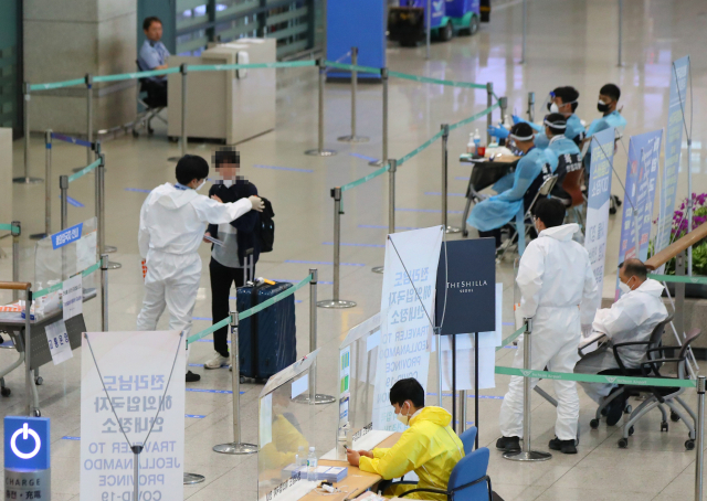 22일 오후 인천국제공항 제1여객터미널 입국장에서 한 입국자가 방역 관계자로부터 설명을 듣고 있다. 연합뉴스