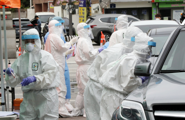 어린이집 원생 남매 2명이 코로나19 확진 판정을 받은 가운데 6일 오전 광주 동구청 주차장에 마련된 임시 드라이브스루 선별진료소에서 동구보건소 직원들이 확진자가 나온 어린이집 원생들과 가족들을 대상으로 검체를 채취하고 있다. 연합뉴스