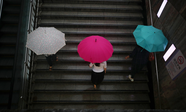 서울 전역에 호우주의보가 발효된 23일 오후 서울 지하철 광화문역에서 퇴근길 시민들이 발걸음을 재촉하고 있다. 연합뉴스