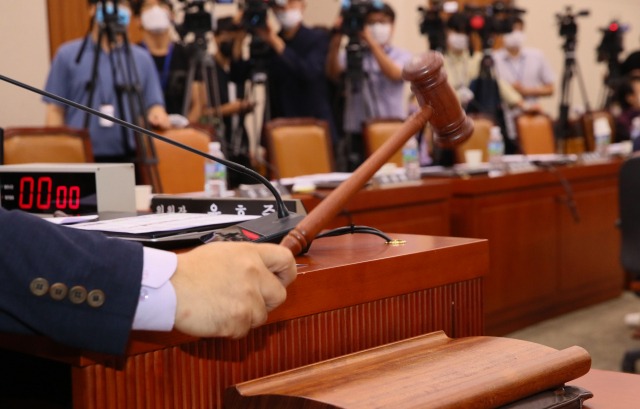 윤호중 국회 법사위원장이 29일 국회 법제사법위원회 전체회의에서 미래통합당 의원들이 퇴장한 가운데 주택임대차보호법 개정안 등 부동산 관련 법안을 가결하고 있다. 의사봉 뒤로 빈 통합당 의원들의 빈 좌석이 보인다. 연합뉴스