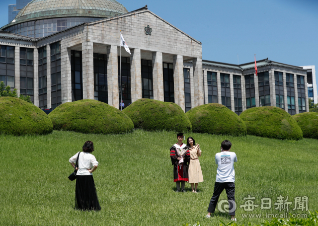 지난 20일 경북대학교 교정에서 한 졸업생이 가족과 함께 졸업 사진을 찍고 있다. 코로나19 재확산으로 대학들이 졸업식을 취소하거나 축소하자 이를 아쉬워하는 졸업생들이 졸업가운을 대여해 사진만 찍는 