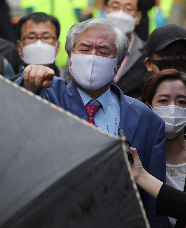 보석 취소로 재수감되는 전광훈 목사가 7일 오후 성북구 사랑제일교회 앞에서 기자회견 전 자신을 가리던 파라솔과 우산을 치우라는 손짓을 하고 있다. 연합뉴스