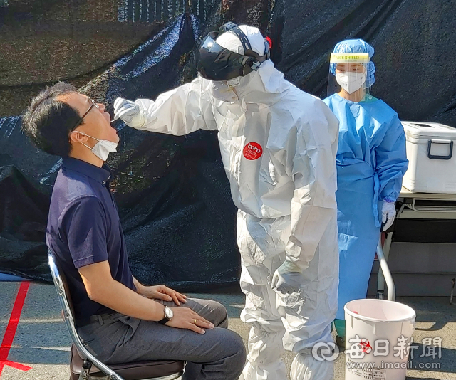 지난 8일 대구 수성구보건소 코로나19 선별진료소에서 의료진이 진단 검사 대상자인 모현철 기자의 검체를 채취하고 있다. 모 기자는 다음 날 음성 결과를 통보 받기 전까지 24시간 피 말리는 자가 격리를 했다. 정운철 기자 woon@imaeil.com