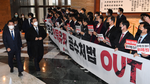 국민의힘 의원들이 9일 국회 본회의장 입구에서 본회의에 참석하는 여당 의원들을 향해 공수처법 저지 등이 적힌 손팻말을 들어보이고 있다. 연합뉴스