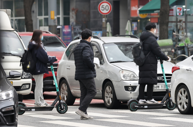 전동킥보드의 자전거도로 주행이 가능이 가능해지는 내용등을 담은 개정 도로교통법·자전거 이용 활성화에 관한 법률이 시행에 들어간 10일 오후 서울 회기역 인근에서 시민들이 전동킥보드를 탄 채 횡단보도를 건너고 있다. 연합뉴스