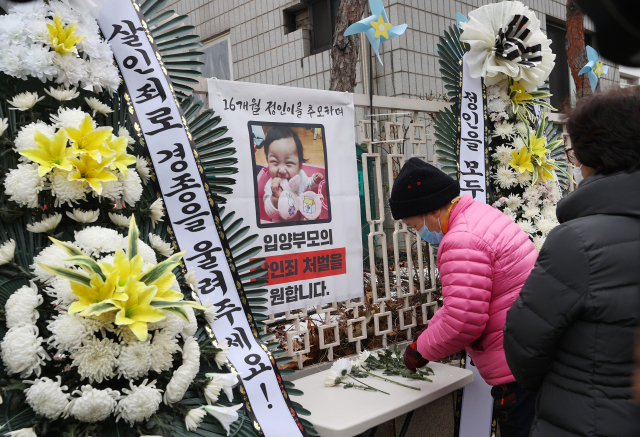 11일 오전 서울 양천구 남부지방검찰청 앞에 설치된 정인이 사진에 시민이 헌화를 하고 있다. 이날 대한아동학대방지협회는 정인이 양부모 재판을 앞두고 엄벌을 촉구하며 근조화환과 바람개비를 설치했다. 연합뉴스