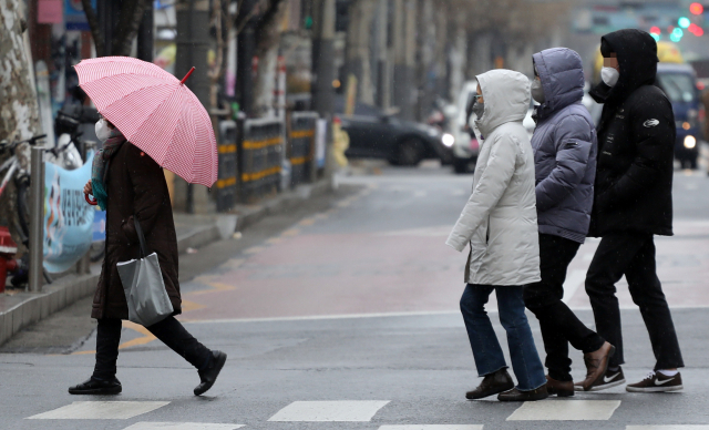 겨울비가 내린 21일 서울 시내에서 한 시민이 우산을 쓰고 있다. 우산이 없는 사람들은 모자를 썼다. 연합뉴스