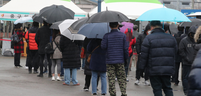 국내 신종 코로나바이러스 감염증(코로나19) 상황이 완만한 감소 국면으로 돌아선 가운데 26일 신규 확진자는 300명대 중반을 나타냈다. 사진은 26일 오전 서울역광장에 설치된 임시선별진료소에서 시민들이 우산을 쓰고 검사를 기다리고 있다. 연합뉴스