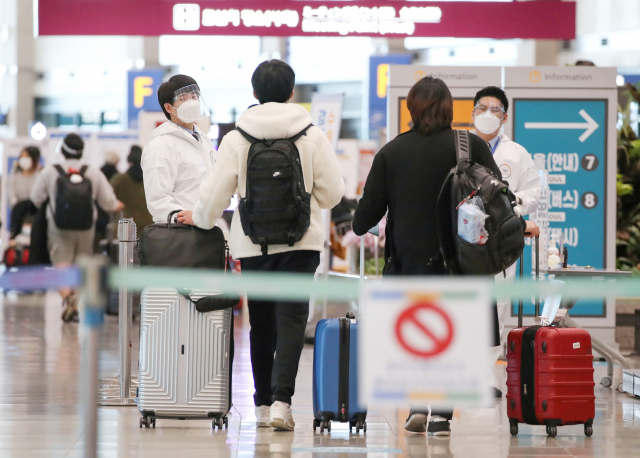 19일 오후 인천국제공항 제1터미널 입국장에서 해외입국자들이 방역관계자로부터 안내를 받고 있다. 연합뉴스