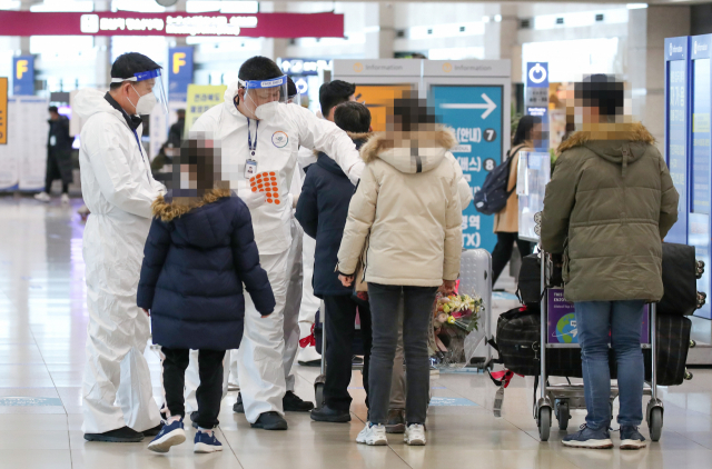 인천국제공항 제1터미널 입국장에서 해외입국자들이 방역관계자로부터 안내를 받고 있다. 연합뉴스