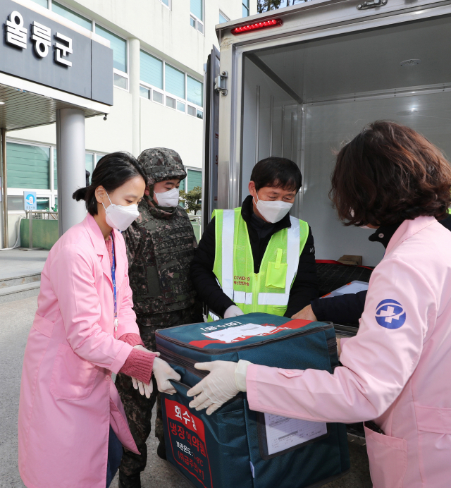 28일 경북 울릉보건의료원에 도착한 코로나19 백신 수송차량 앞에서 의료원 관계자와 이송 담당자가 백신을 옮기고 있다. 국방부 제공. 연합뉴스