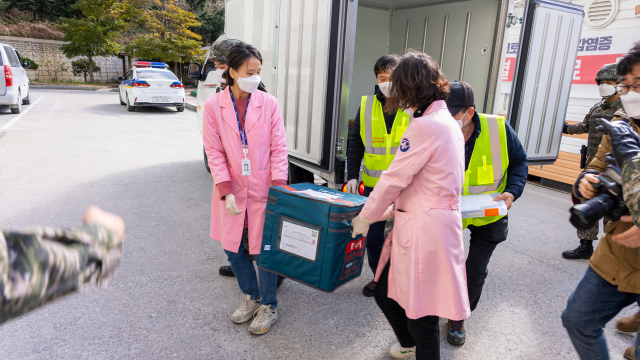 28일 코로나19 백신을 실은 군 수송 헬기가 경북 울릉군 해군부대 헬기장에 도착 후 관계자들이 백신을 울릉군 보건의료원으로 옮기고 있다. 연합뉴스